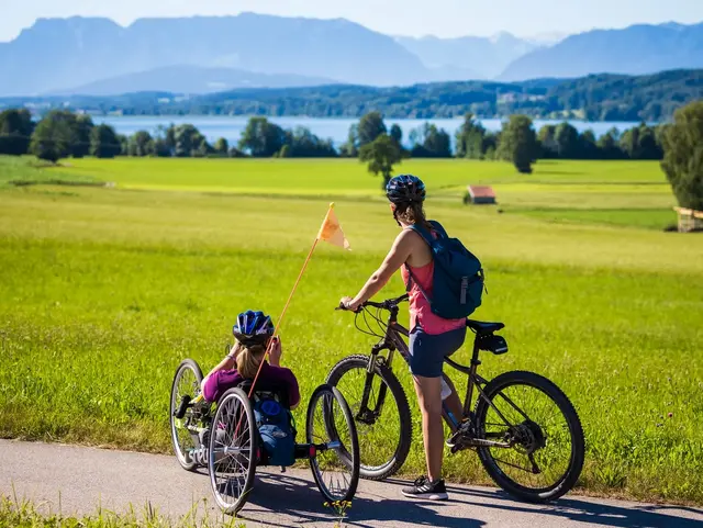 - © Chiemgau Tourismus e.V. Handbikerin mit Radbegleitung am Chiemsee