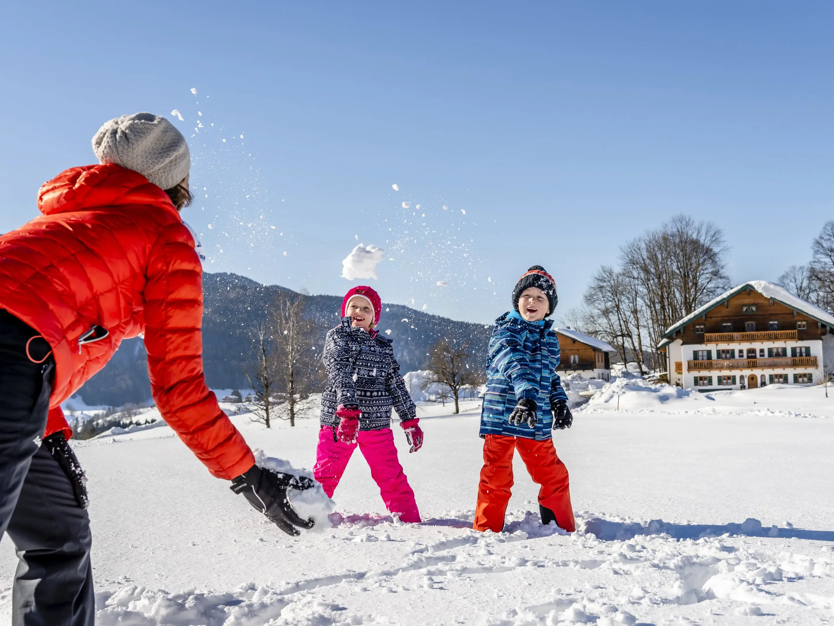 Winterspaß - © Medienservice ProGenuss® Urlaubsfamilie macht eine Schneeballschlacht in herrlicher Umgebung.